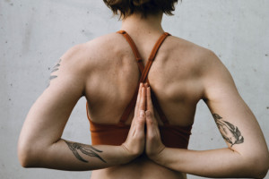 8 häufige Yoga Irrtümer: eine Frau legt ihre Handflächen hinter dem Rücken aneinander und praktiziert die Reverse Prayer Pose